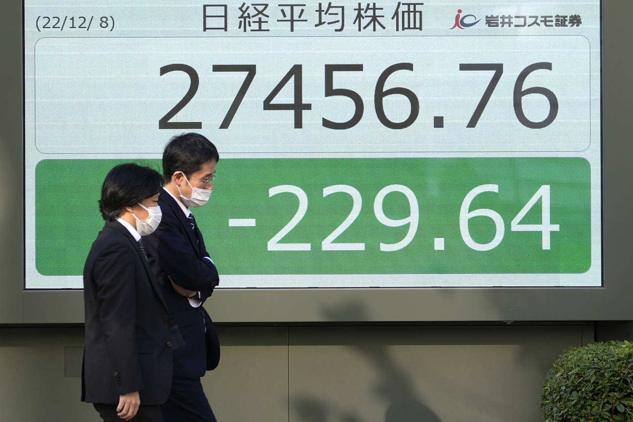 People walk past an electronic stock board showing Japan's Nikkei 225 index at a securities firm Th...