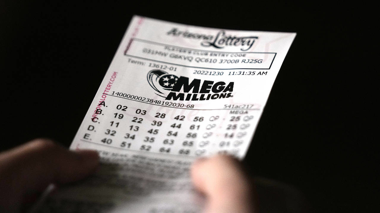 A person holds a Mega Millions lottery ticket in Tempe, Ariz., Friday, Dec. 30, 2022. The jackpot f...