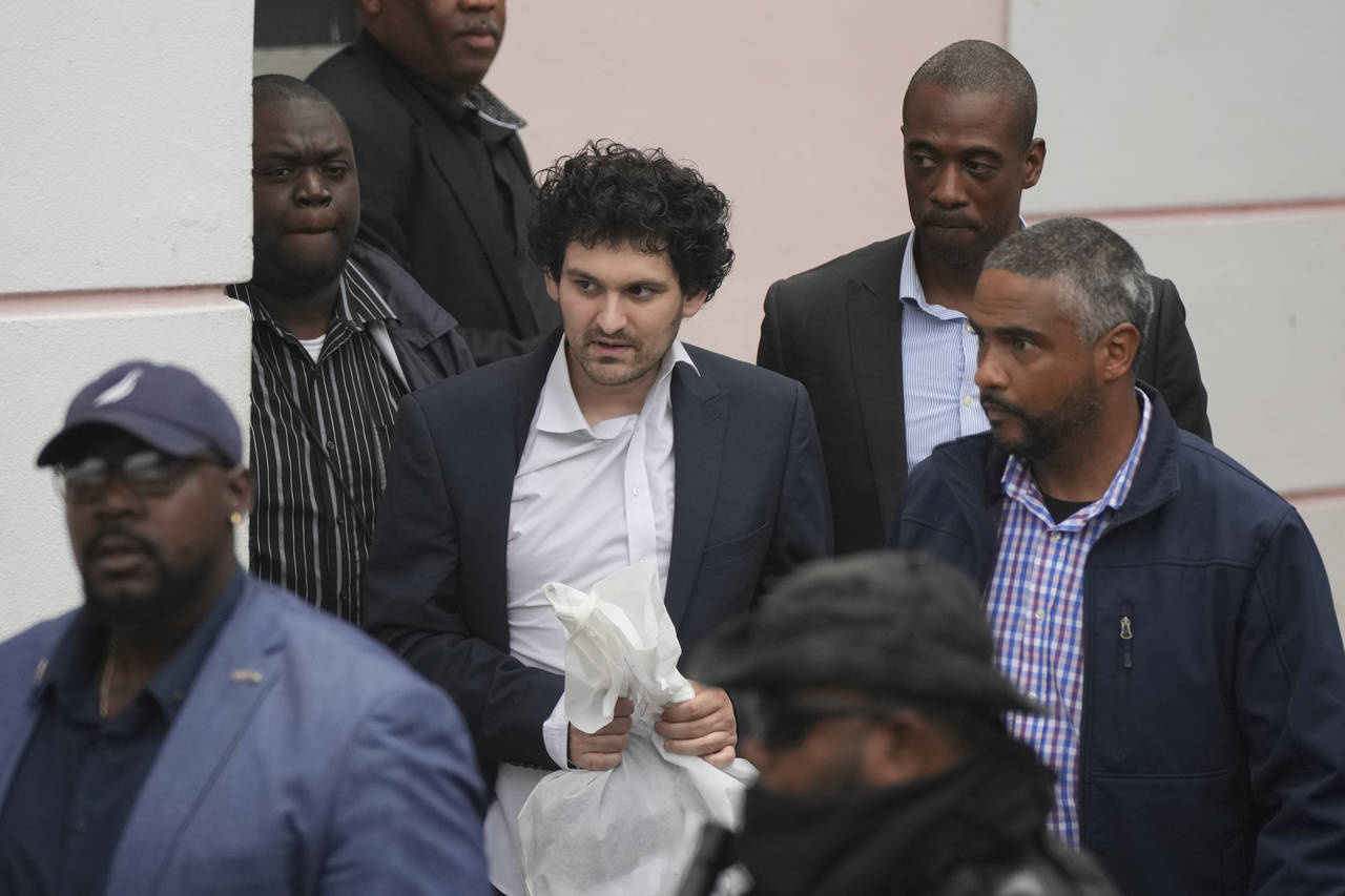 FTX founder Sam Bankman-Fried, center, is escorted from the Magistrate Court in Nassau, Bahamas, We...