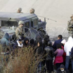 
              Migrants congregate on the banks of the Rio Grande at the U.S. border with Mexico on Tuesday, Dec. 20, 2022, in El Paso, Texas, where members of the Texas National Guard cordoned off a gap in the U.S. border wall. Restrictions that prevented many from seeking asylum in the U.S. have remained in place beyond their anticipated end. (AP Photo/Morgan Lee)
            