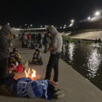 
              Migrants congregate at campfires on the banks of the Rio Grande in Ciudad Juárez, Mexico, as others wade through shallow waters toward the United States and its border wall on Tuesday, Dec. 20, 2022. Restrictions that prevented many from seeking asylum in the U.S. remained in place beyond their anticipated end. (AP Photo/Morgan Lee)
            