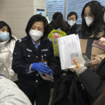 
              An officer collects passports from residents for renewal and re-applications at a community police station in Beijing, Wednesday, Dec. 28, 2022. China says it will resume issuing passports for tourism in another big step away from anti-virus controls that isolated the country for almost three years, setting up a potential flood of Chinese going abroad for next month's Lunar New Year holiday. (AP Photo/Ng Han Guan)
            