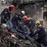 
              Rescue workers transfer the body of a man killed in a Russian missile strike on an apartment building, into a plastic bag in the southeastern city of Dnipro, Ukraine, Monday, Jan. 16, 2023. (AP Photo/Evgeniy Maloletka)
            