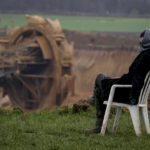 
              A person sits in a chair next to the Garzweiler lignite opencast mine at the Luetzerath village near Erkelenz, Germany, Tuesday, Jan. 10, 2023.  Environmental activists were locked in a standoff with police this week around the hamlet of Luetzerath that's due to be bulldozed for the expansion of a nearby lignite mine. (AP Photo/Michael Probst)
            