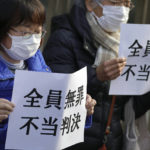
              Yoshiko Furukawa, left, and Etsuko Kudo, right, supporters of the plaintiff hold a cloth sign that reads "All not guilty, Unfair judgment," outside of the Tokyo High Court in Tokyo Wednesday, Jan. 18, 2023. The court on Wednesday found three former executives of Tokyo Electric Power Company not guilty of negligence over the 2011 Fukushima nuclear meltdowns and subsequent deaths of more than 40 elderly residents during their forced evacuation. (AP Photo/Eugene Hoshiko)
            