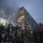 
              Emergency workers clear the rubble after a Russian rocket hit a multistory building leaving many people under debris in Dnipro, Ukraine, Saturday, Jan. 14, 2023. (AP Photo/Roman Chop)
            