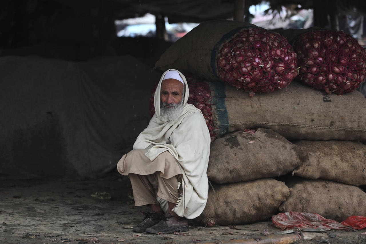 FILE - A produce vendor waits for customers at a market in Islamabad, Pakistan, on Jan. 22, 2022. G...