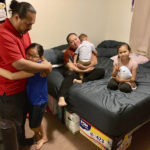 
              The five-member Purdy family gather in one of two bedrooms they share in a house they rent with extended family in Kapolei, Hawaii, on Wednesday, Dec. 14, 2022. The family moved to Las Vegas in 2017 to escape Hawaii's high cost of living and returned last year and share two bedrooms in a home they rent with extended family. Native Hawaiians, like the Purdys, who have been priced out of Hawaii are finding more affordable places to live in cities like Las Vegas. (AP Photo/Jennifer Sinco Kelleher)
            