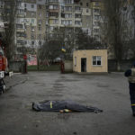 
              A firefighter passes by the dead body of a firefighter killed in the Russian shelling of the fire station in Kherson, Ukraine, on the Orthodox Christmas Eve Friday, Jan. 6, 2023. (AP Photo/LIBKOS)
            