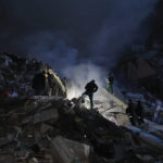 
              Emergency workers clear the rubble after a Russian rocket hit a multistory building leaving many people under debris in Dnipro, Ukraine, Saturday, Jan. 14, 2023. (AP Photo/Roman Chop)
            