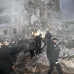 
              Emergency workers clear the rubble after a Russian rocket hit a multistory building leaving many people under debris in Dnipro, Ukraine, Saturday, Jan. 14, 2023. (AP Photo/Roman Chop)
            