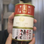 
              CORRECTS THE PHOTOGRAPHER'S NAME TO KWIYEON HA - Staff of Kyodo Senpaku Co. holds canned whale meat sold from a vending machine at the firm's unmanned store Thursday, Jan. 26, 2023, in, Yokohama, Japan. The Japanese whaling operator, after struggling for years to promote its controversial products, has found a new way to cultivate clientele and bolster sales: whale meat vending machines. (AP Photo/Kwiyeon Ha)
            