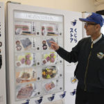 Konomu Kubo, a spokesperson for Kyodo Senpaku Co. explains how whale meat is being sold from a vending machine at the firm's store, Thursday, Jan. 26, 2023, in Yokohama, Japan. The Japanese whaling operator, after struggling for years to promote its controversial products, has found a new way to cultivate clientele and bolster sales: whale meat vending machines. (AP Photo/Ha Kwyeon)