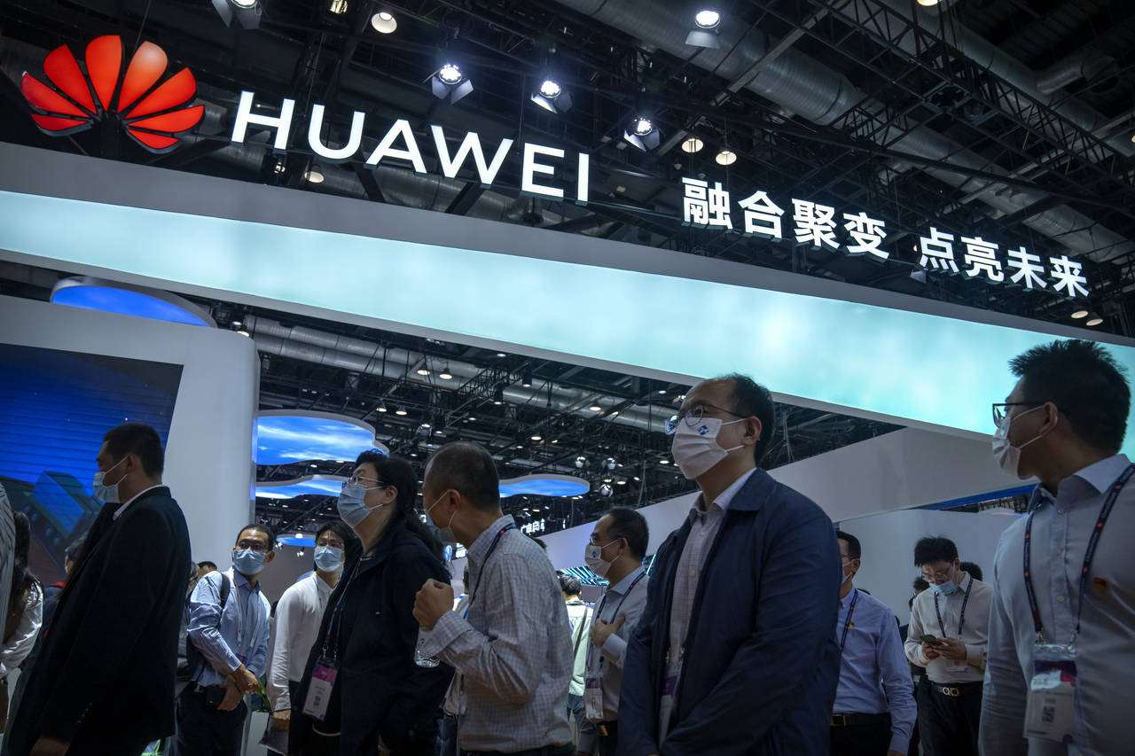 FILE - Visitors walk past a booth for Chinese technology firm Huawei at the PT Expo in Beijing on S...