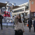 
              A woman takes a selfie as visitors wearing face masks tour past an outdoor shopping center displaying a Mickey Mouse statue commemorating the Disney 100th anniversary, in Beijing, Thursday, Jan. 5, 2023. As COVID-19 rips through China, other countries and the WHO are calling on its government to share more comprehensive data on the outbreak, with some even saying many of the numbers it is reporting are meaningless. (AP Photo/Andy Wong)
            