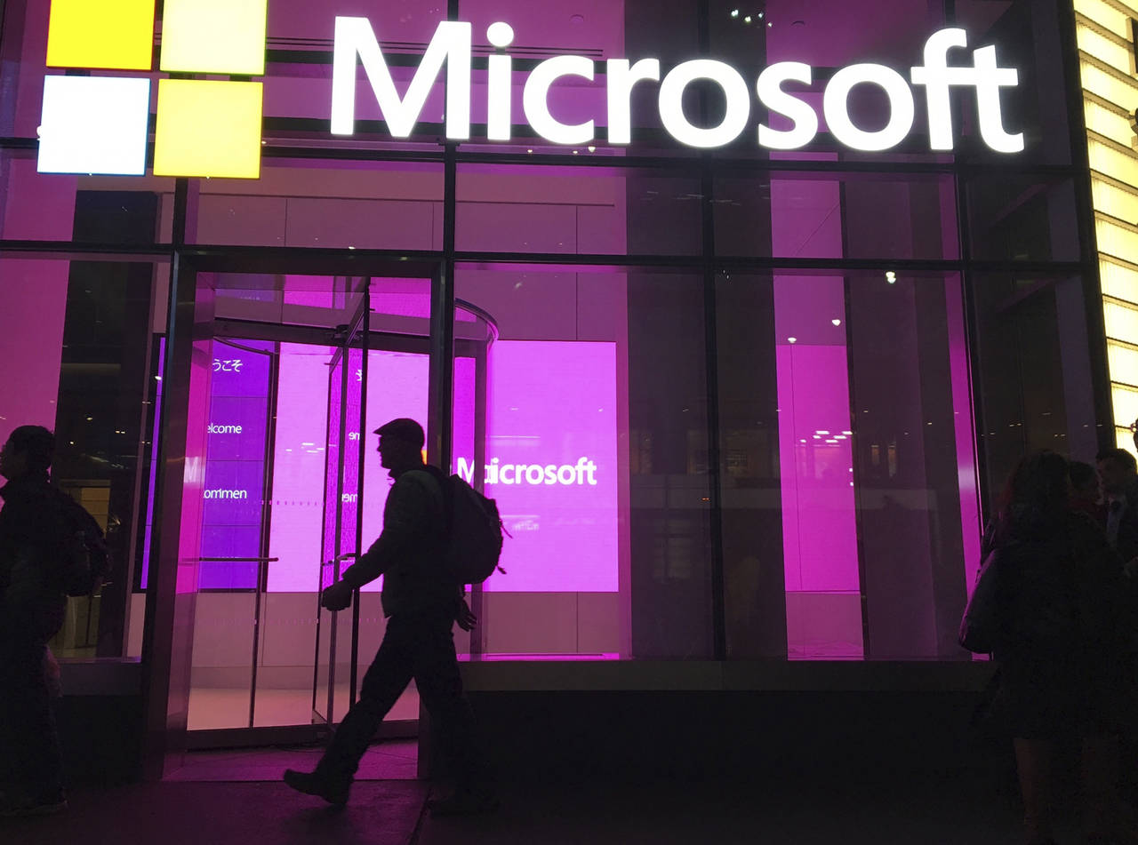 FILE - In this Nov. 10, 2016, file photo, people walk past a Microsoft office in New York. Microsof...