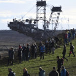 
              Climate protection activists stand in front of a bucket wheel excavator on the edge of the open pit mine in Luetzerath, Germany, Sunday, Jan.8, 2023 Luetzerath is to be mined for the expansion of the Garzweiler II opencast lignite mine. (Henning Kaiser/dpa via AP)
            