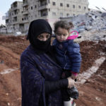 
              Ayesha and 12 of her family members who lost their home in the devastating earthquake, carries her granddaughter in Atareb, Syria, Sunday, Feb. 12, 2023. After the earthquake, the 43-year-old has had no access to water, electricity, or heat for her and 11 other family members, crammed into a tent after their home in the northwest Syrian town of Atareb was leveled. Now added to the litany of hardships for women is destruction from the earthquake, which killed tens of thousands and left millions more homeless in southern Turkey and northern Syria. (AP Photo/Hussein Malla)
            