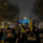 
              Protestors arrive at the Brandenburg Gate, illuminated in Ukrainian colors, during a demonstration to mark the first anniversary of Russia's full-scale invasion of Ukraine, in Berlin, Germany, Friday, Feb. 24, 2023. (AP Photo/Markus Schreiber)
            