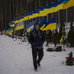 
              An undertaker walks by the Alley of Heroes at the Irpin Cemetery in Ukraine, Monday, Feb. 6, 2023. (AP Photo/Daniel Cole)
            