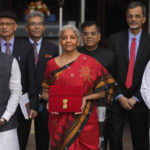 
              Indian Finance Minister Nirmala Sitharaman, in red, poses for the media holding a pouch containing a digital tablet as she leaves her office along with her colleagues for President's house before presenting the federal budget for the financial year 2023-24  in the Parliament in New Delhi, India, Wednesday, Feb. 1 2023. (AP Photo/Manish Swarup)
            