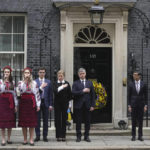 
              Britain's Prime Minister Rishi Sunak, third right, and his wife Akshata Murty, second right, with Ukrainian Ambassador to the UK, Vadym Prystaiko, center, his wife Inna and members of the Ukrainian Armed Forces outside 10 Downing Street in London, as they observe a minute's silence to mark the one-year anniversary of the Russian invasion of Ukraine, Friday, Feb. 24, 2023. (AP Photo/Kin Cheung)
            