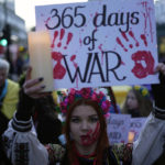 
              A Ukrainian supporter holds a placard to mark the one-year anniversary of the full-scale Russian invasion of Ukraine, as they march to Russian Embassy, in London, Friday, Feb. 24, 2023. (AP Photo/Kin Cheung)
            