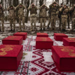 
              Medals are placed on a table as Ukrainian servicemen of the Prince Roman the Great 14th Separate Mechanized Brigade adjust their hats before a flag ceremony where some of them were honored for their bravery and accomplishments in battle, in the Kharkiv area, Ukraine, Saturday, Feb. 25, 2023. (AP Photo/Vadim Ghirda)
            