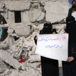 
              FILE - Women stand amidst the rubble of destroyed houses with placards in Arabic reading "United Nations are the partners of Bashar Assad and killing Syrians," in Atareb, Syria, Sunday, Feb. 12, 2023. The massive earthquake that hit last week is the latest in a litany of hardships for Syrian women, many of whom have been left dependent on aid and alone responsible for their families' well-being. (AP Photo/Hussein Malla, File)
            