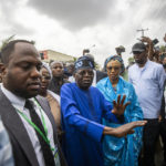
              Presidential candidate Bola Tinubu of the All Progressives Congress, center, accompanied by his wife, Oluremi Tinubu, center-right, arrives to cast his vote in the presidential elections in Lagos, Nigeria, Saturday, Feb. 25, 2023. Voters in Africa's most populous nation are heading to the polls Saturday to choose a new president, following the second and final term of incumbent Muhammadu Buhari. (AP Photo/Ben Curtis)
            