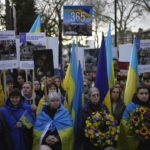 
              Ukrainians supporters hold flags to mark the one-year anniversary of the full-scale Russian invasion of Ukraine, as they march to Russian Embassy, in London, Friday, Feb. 24, 2023. (AP Photo/Kin Cheung)
            