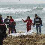 
              Italian Red Cross volunteers and coast guards recover a body after a migrant boat broke apart in rough seas, at a beach near Cutro, southern Italy, Sunday, Feb. 26, 2023. Rescue officials say an undetermined number of migrants have died and dozens have been rescued after their boat broke apart off southern Italy.(Antonino Durso/LaPresse via AP)
            