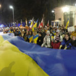 
              Participants carry a giant Ukrainian flag to mark the one year anniversary of the Russian invasion of Ukraine, in front of the Russian Embassy in Warsaw, Poland, Friday, Feb. 24, 2023. (AP Photo/Czarek Sokolowski)
            