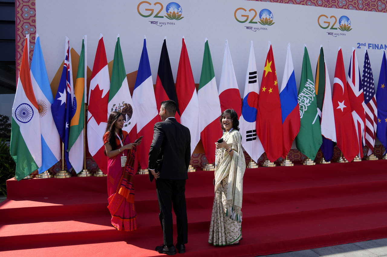 Delegates interact in front of flags of participating countries displayed at the venue of G-20 fina...