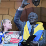 
              Ukrainian Katerina Kalinina draped her country's flag on a statue of former South African President Nelson Mandela during a demonstration on the one year anniversary of the Russian invasion of Ukraine, at the City Hall in Cape Town, South Africa, Friday, Feb. 24, 2023. (AP Photo/Nardus Engelbrecht)
            