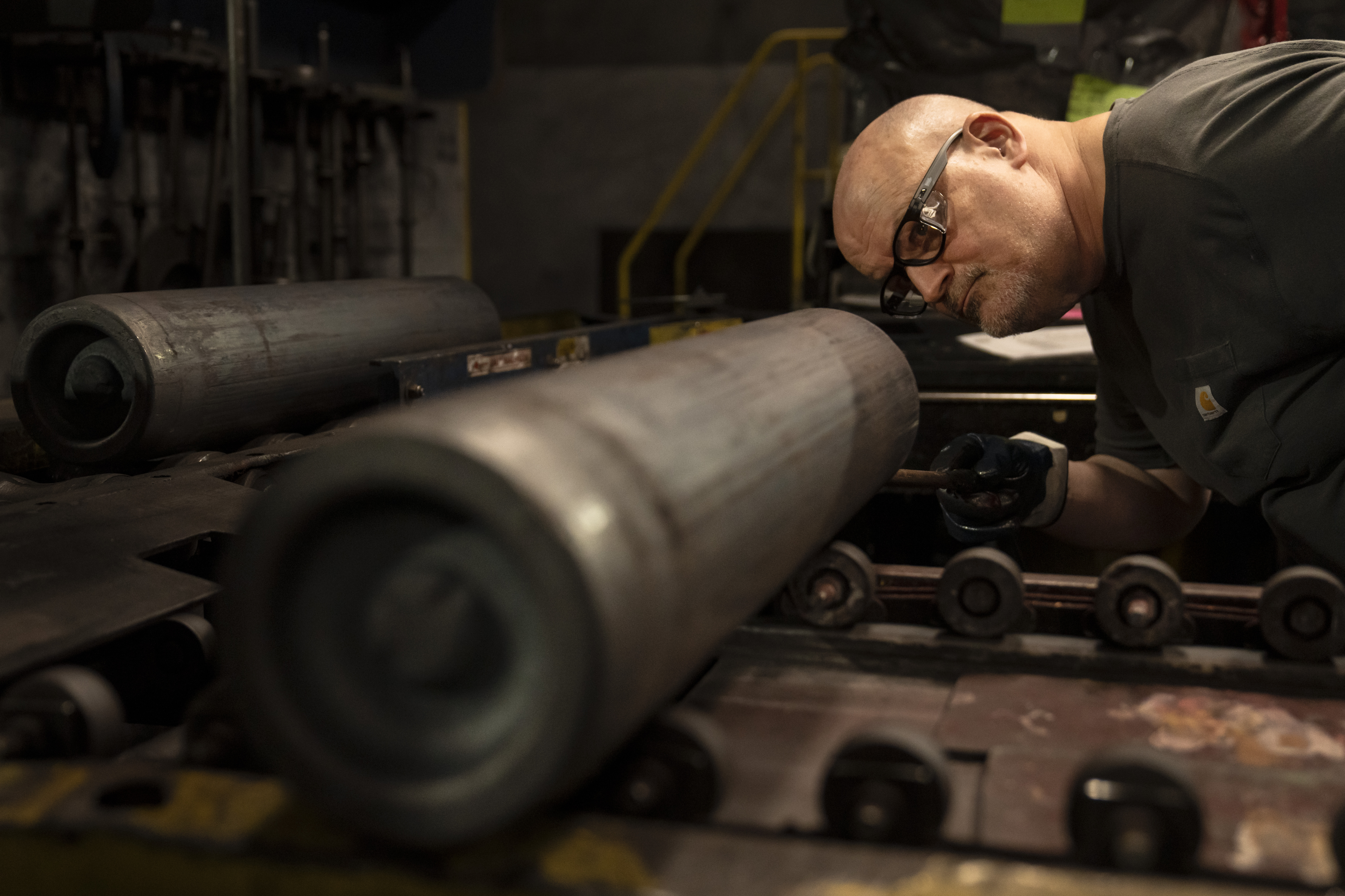 A steel worker inspects a 155 mm M795 artillery projectile during the manufacturing process at the ...