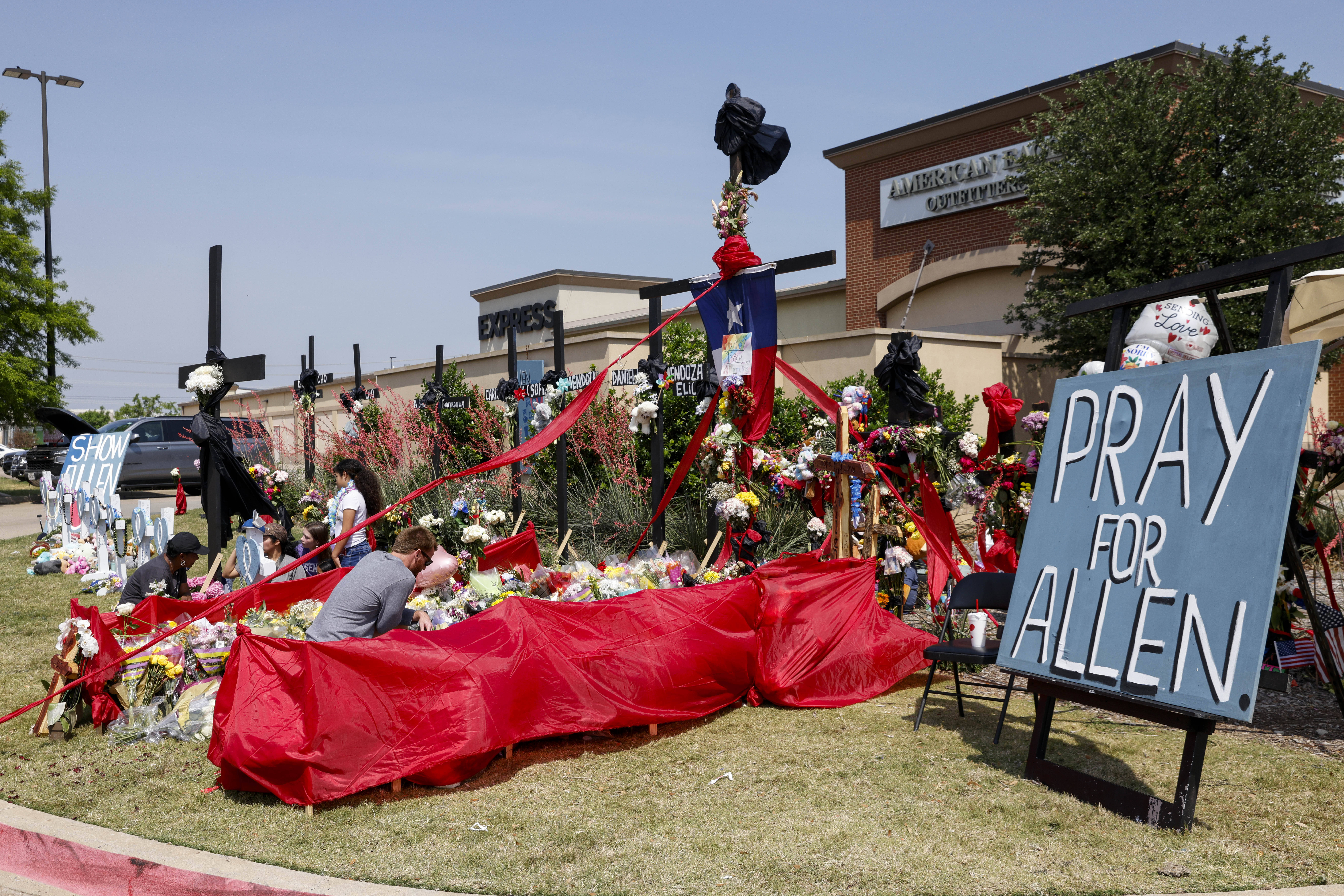 People place flowers and pay their respects at a memorial for victims of the Allen Premium Outlets ...