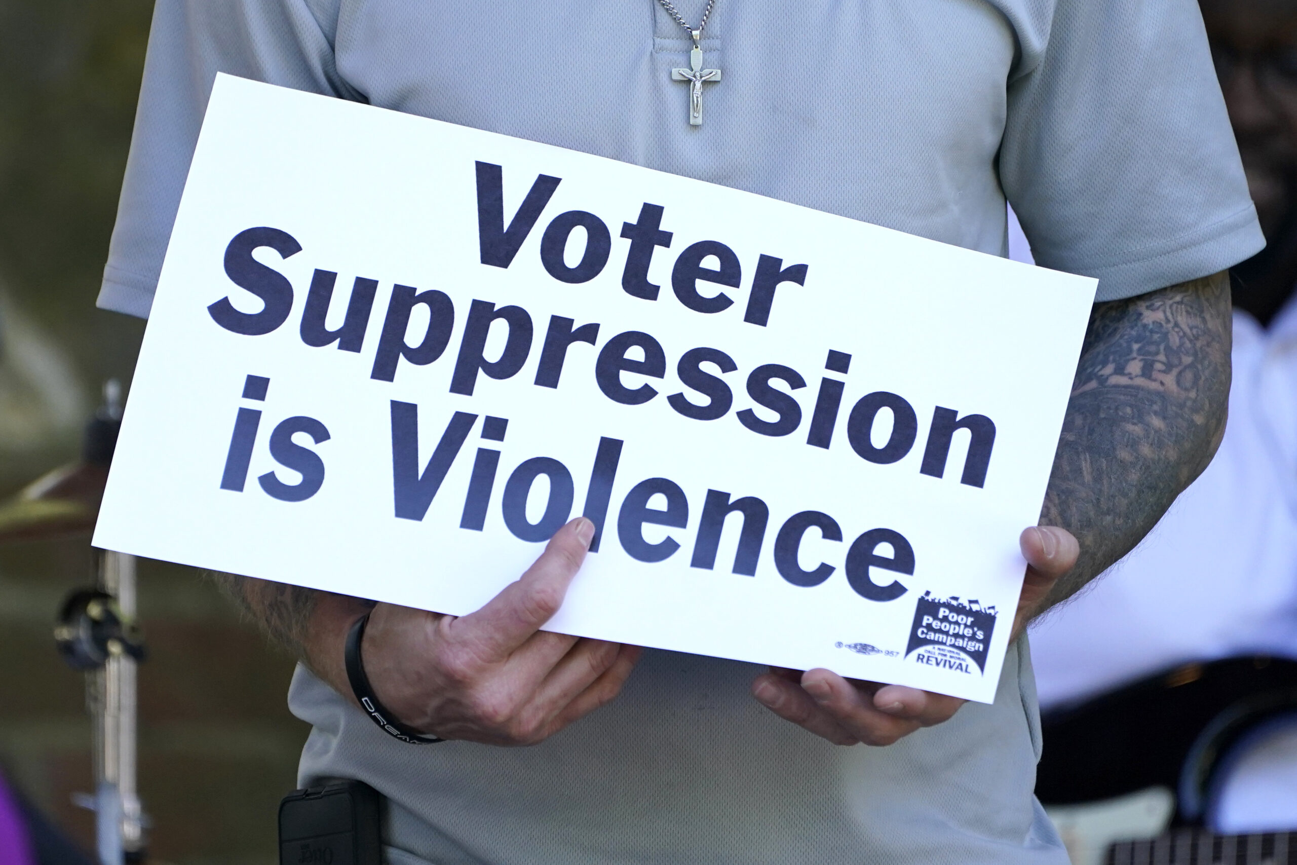 FILE - A person previously convicted of a felony felon holds a sign about voter suppression during ...