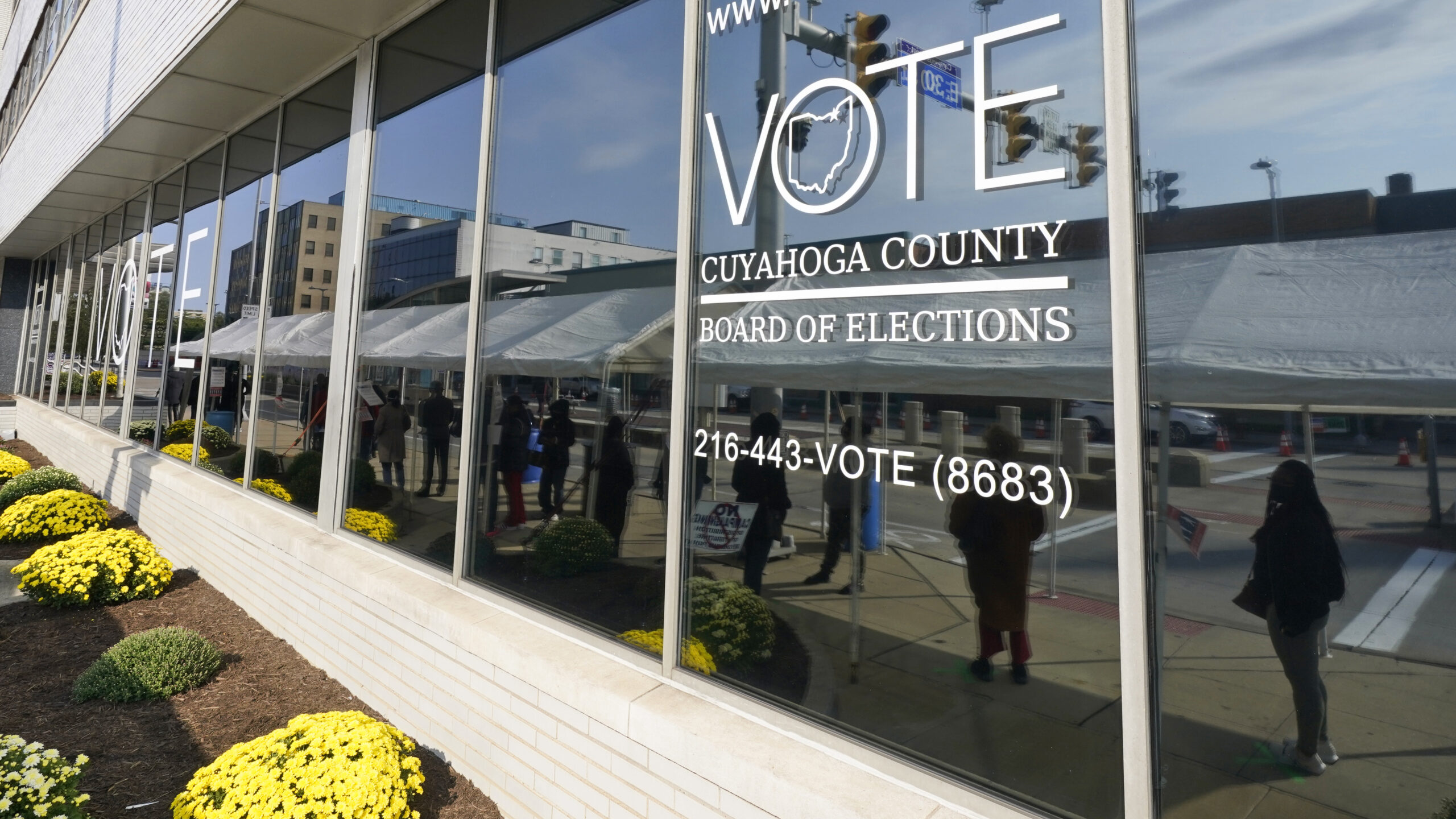 FILE - Voters are reflected in a window as they wait in line to participate in early voting at the ...
