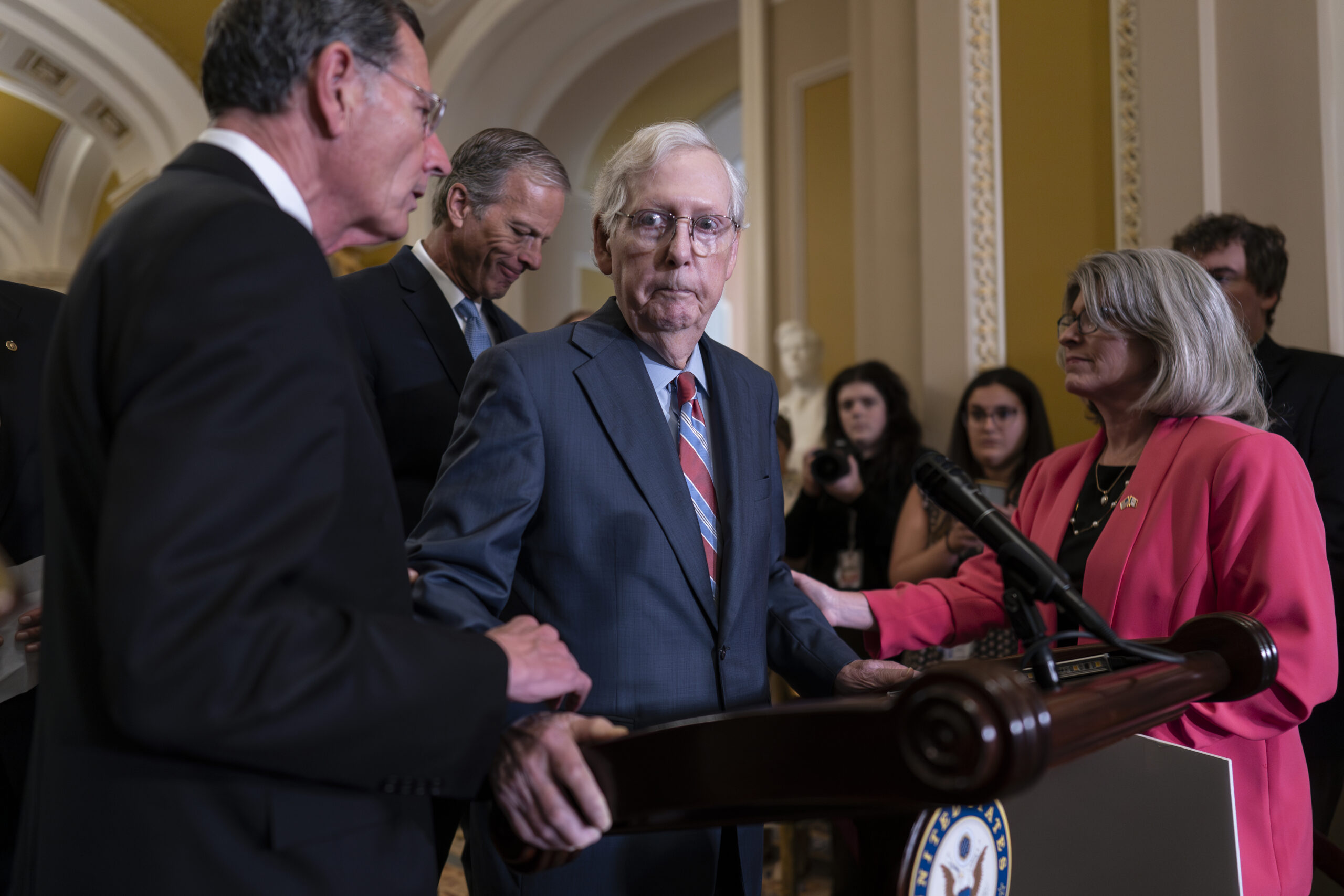 Senate Minority Leader Mitch McConnell, R-Ky., center, is helped by, from left, Sen. John Barrasso,...