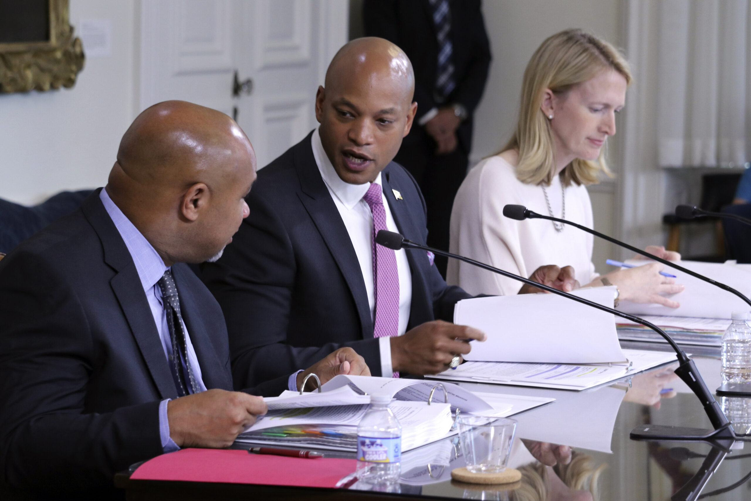 Maryland Gov. Wes Moore, center, talks to Treasurer Dereck Davis during a meeting of the Board of P...
