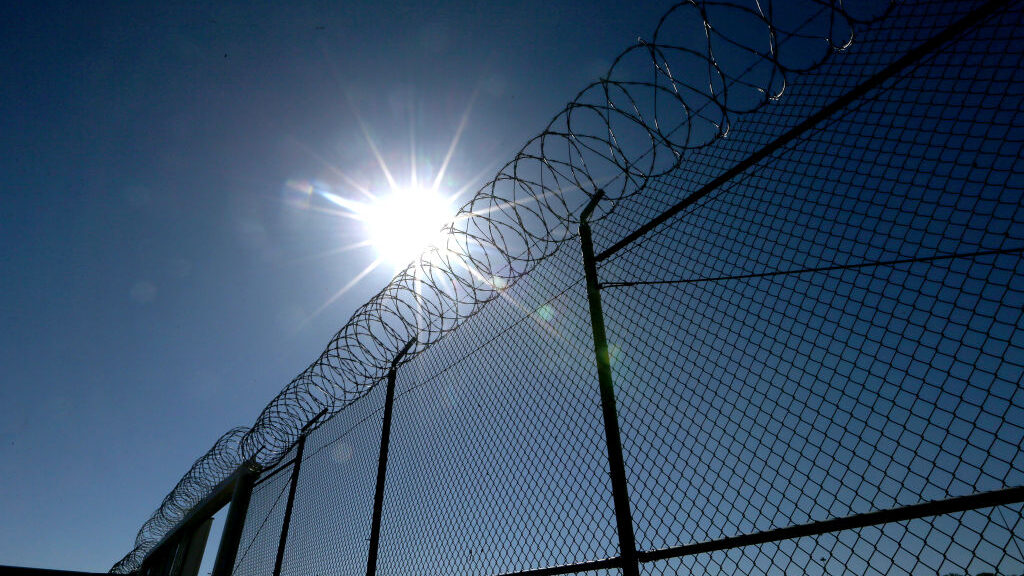 sun shown behind a barb wire fence...