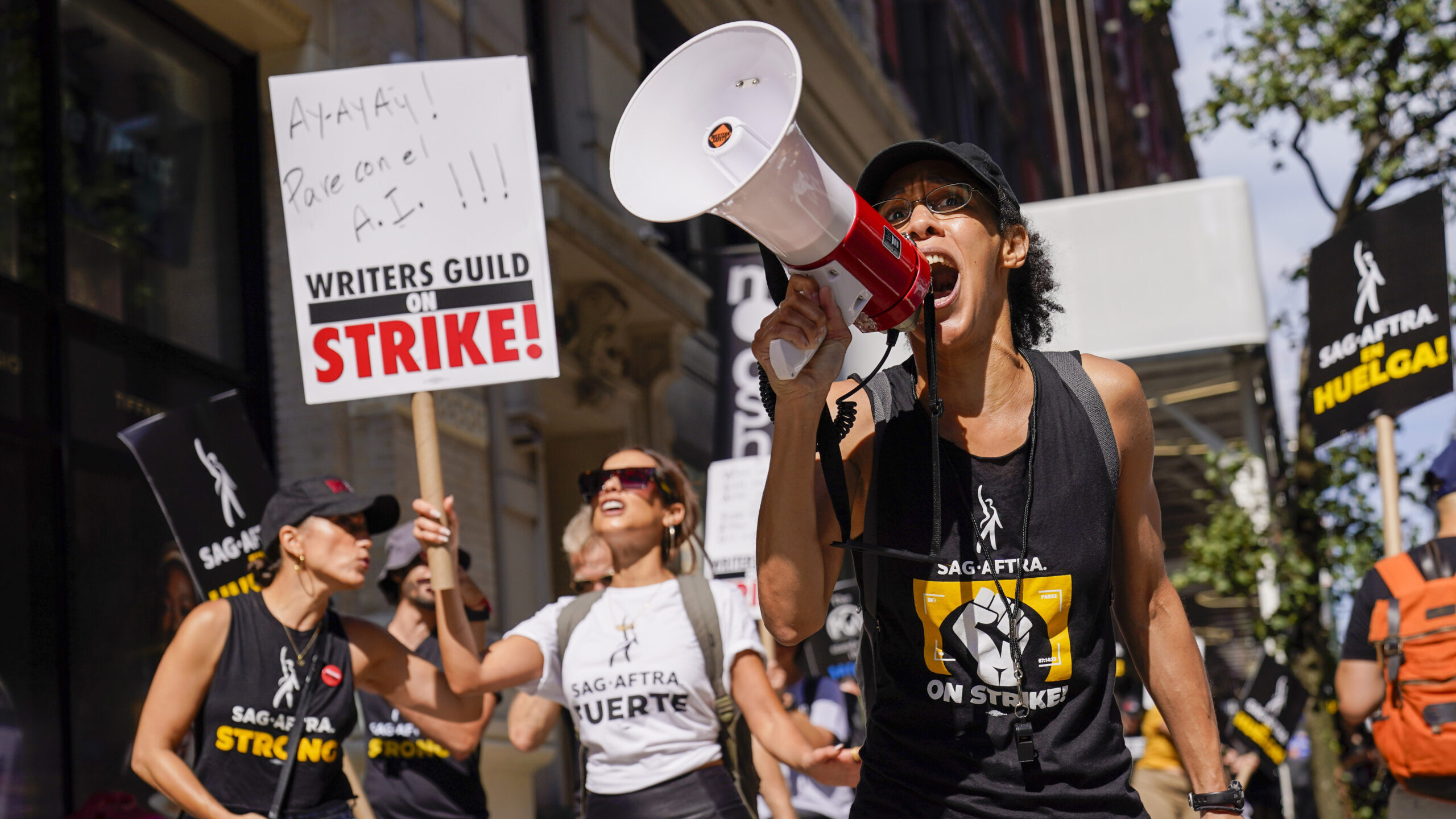 A strike captain, right, leads the chants as strikers walk a picket line outside Warner Bros., Disc...