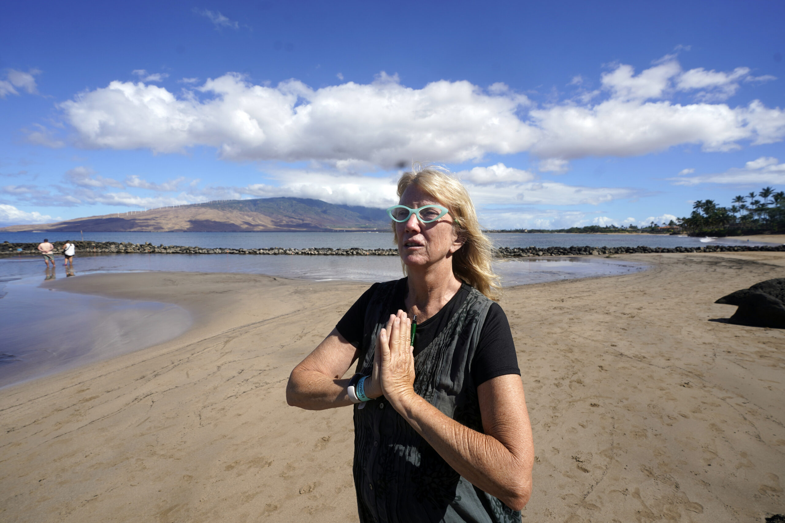 Anne Landon walks along a beach, Tuesday, Aug. 15, 2023, in Kihei, Hawaii. The evacuation center at...