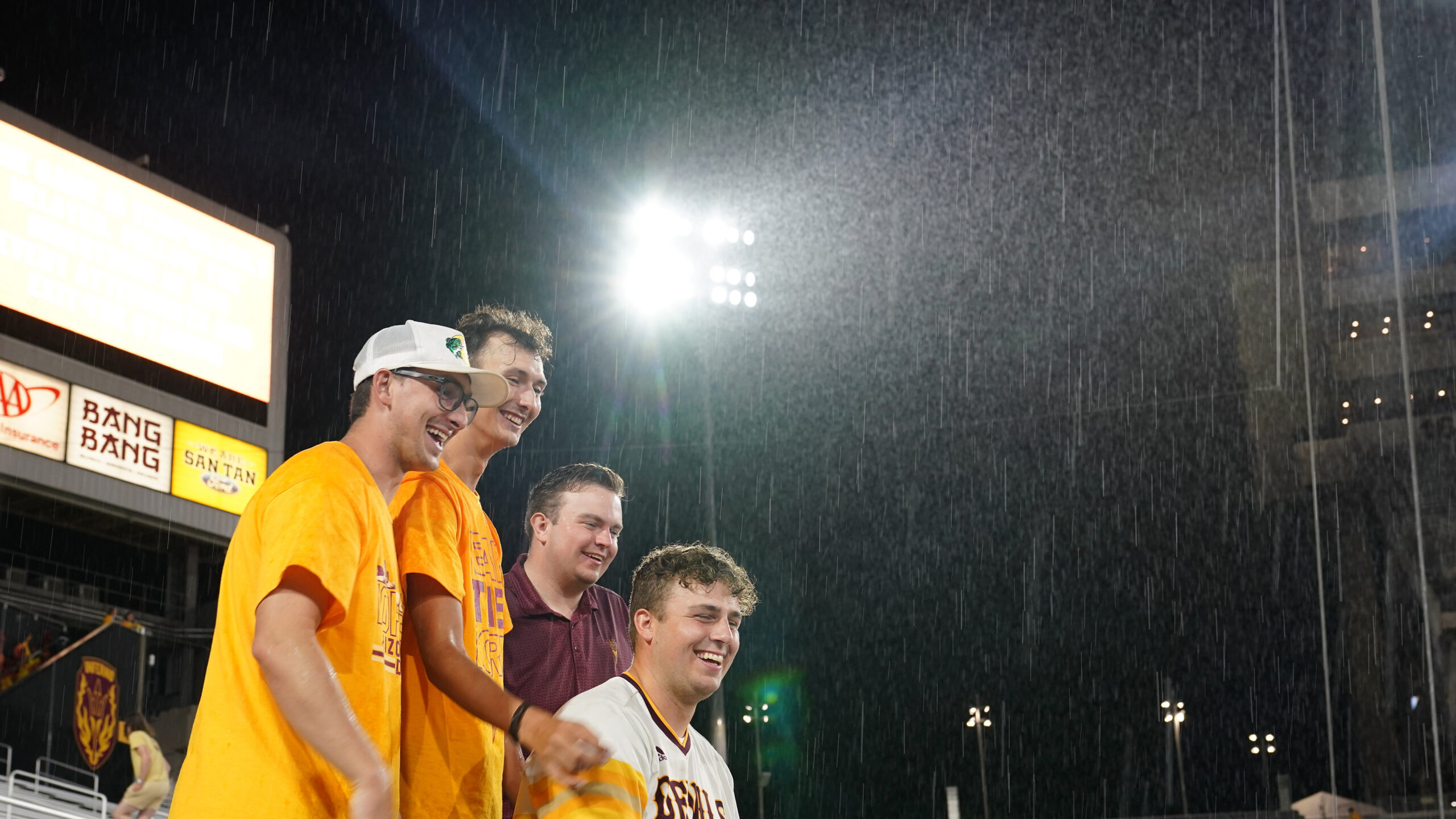 A few Arizona State students stand in the pouring rain during a weather delay of an NCAA college fo...