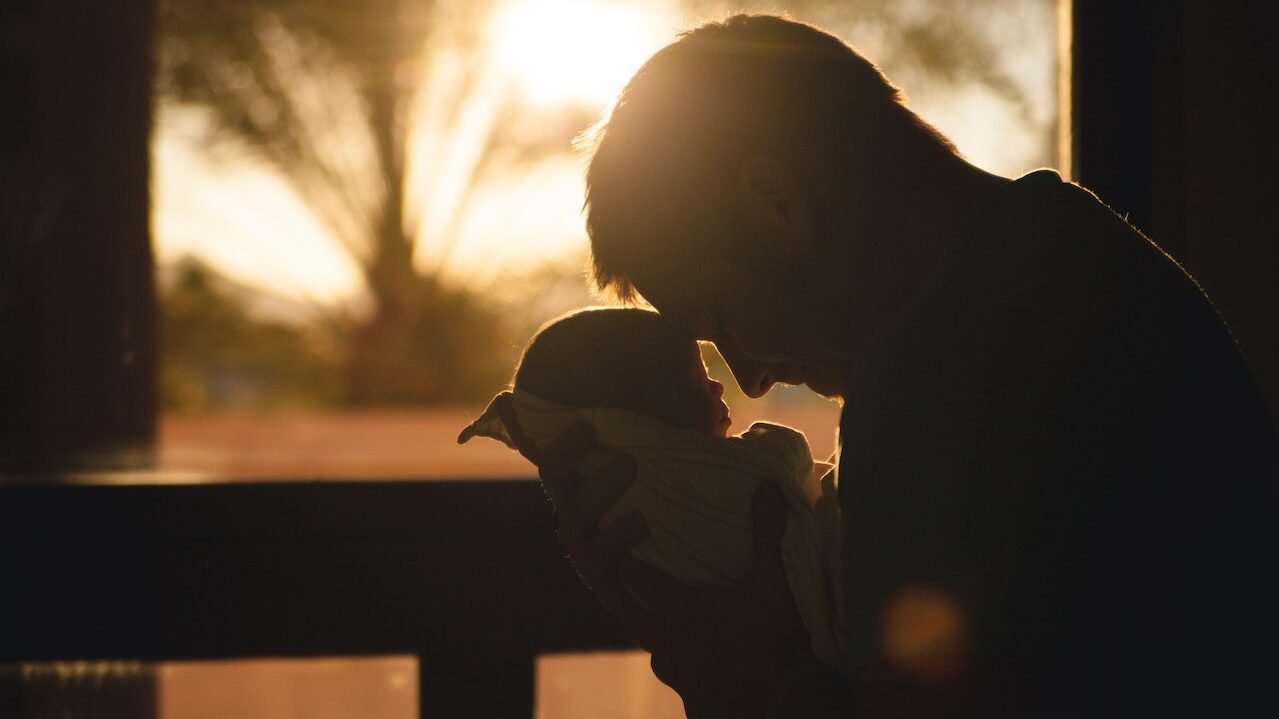 Man holds baby in loving manner...