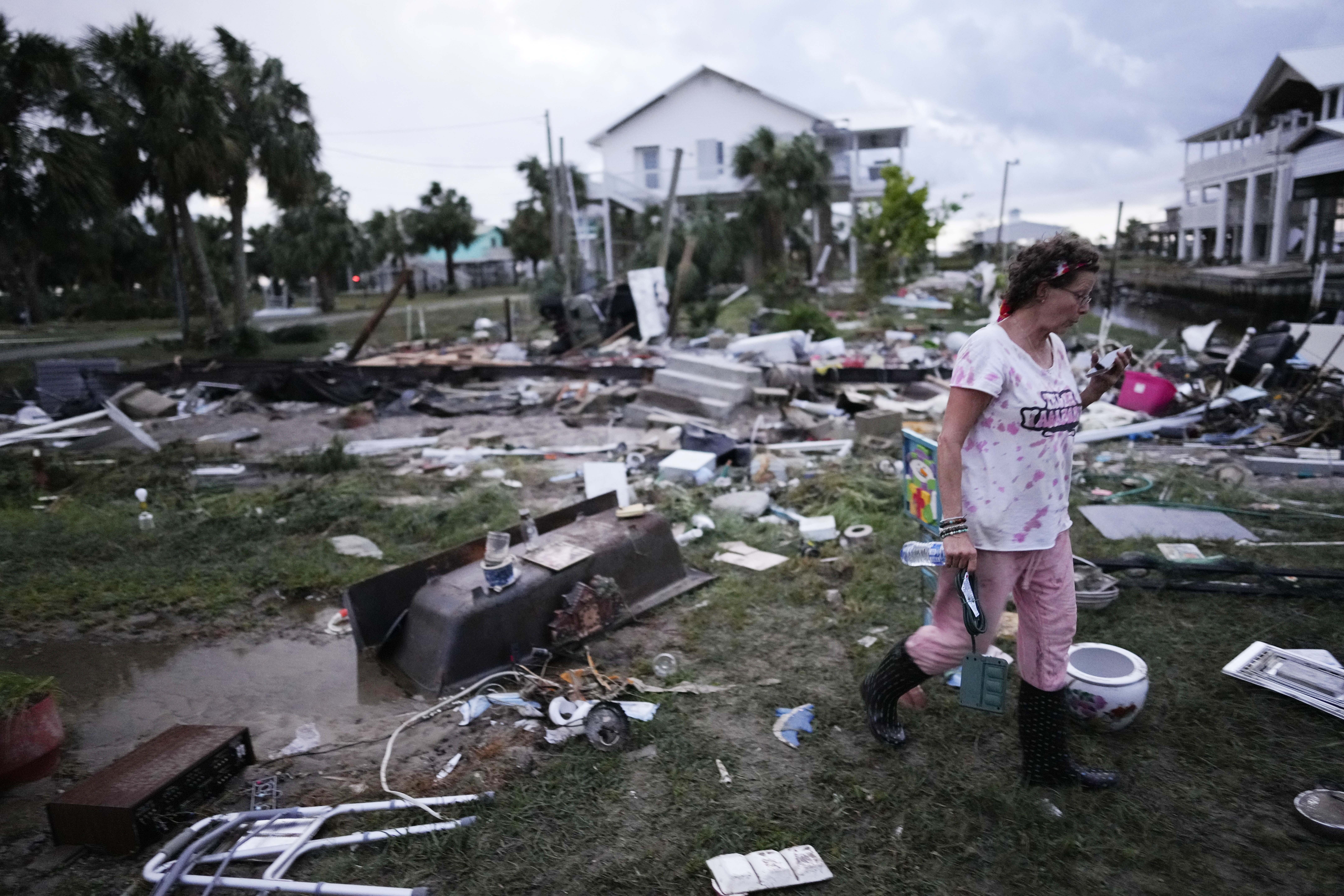 File - Jewell Baggett walks amidst debris strewn across the yard where her mother's home had stood,...