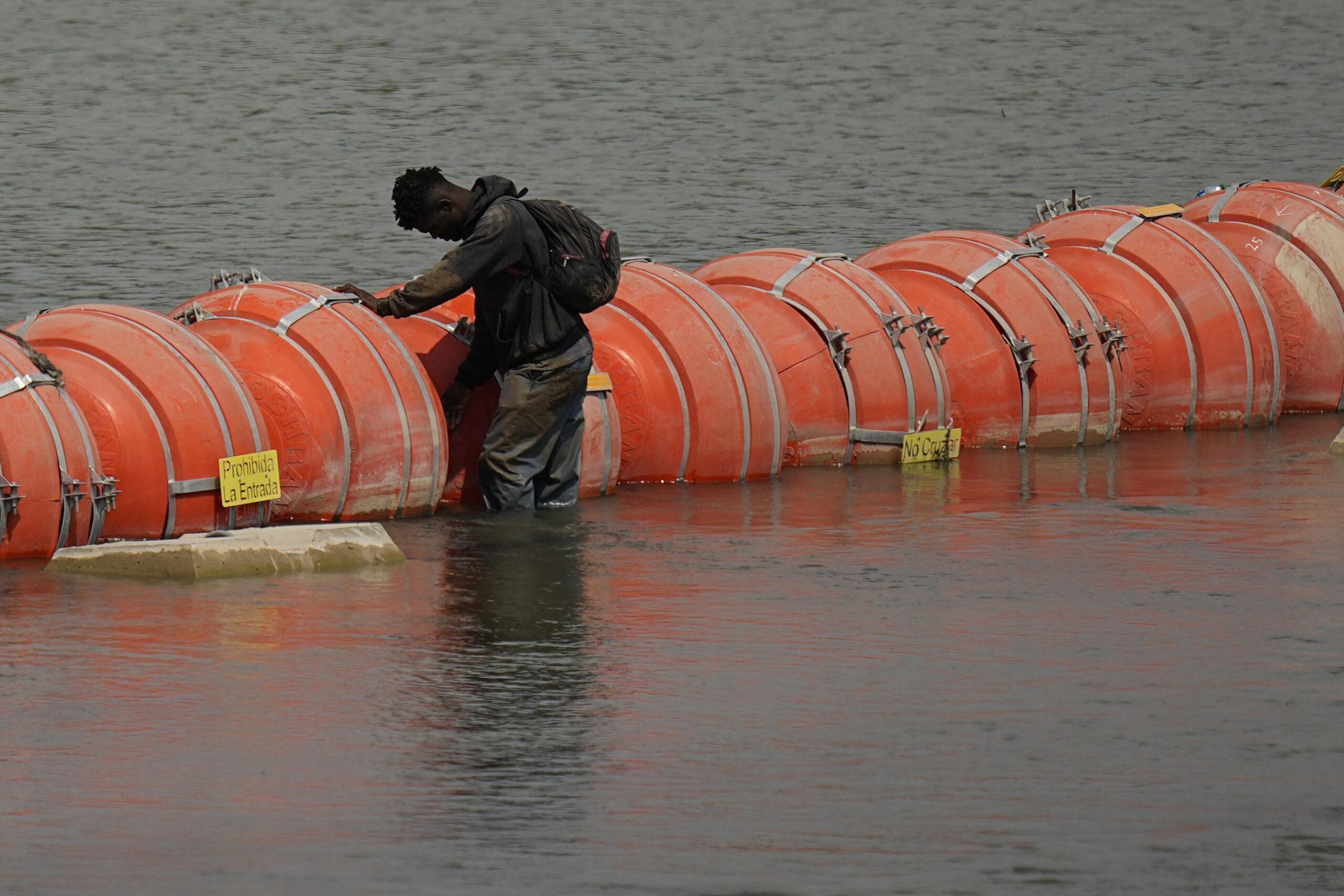 A migrant from Columbia stands at a floating buoy barrier as he looks to cross the Rio Grande from ...