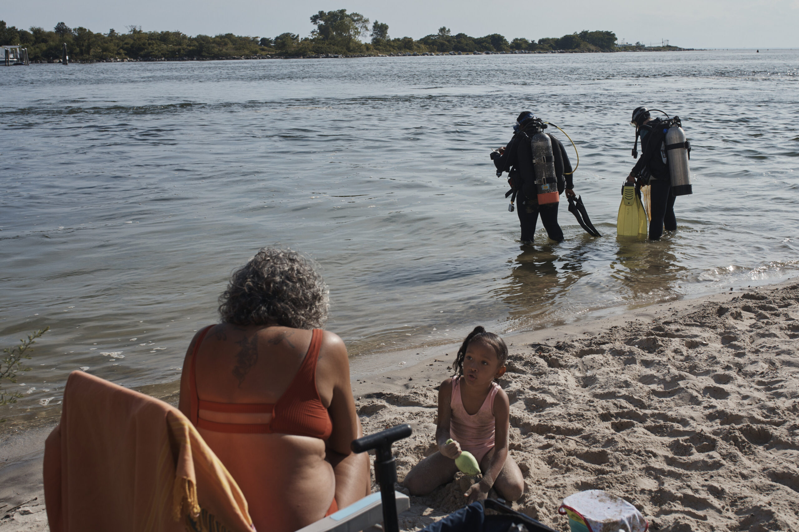 A family spends time on the beach as scuba divers, Tanasia Swift, second right, and Sarah Sears fir...