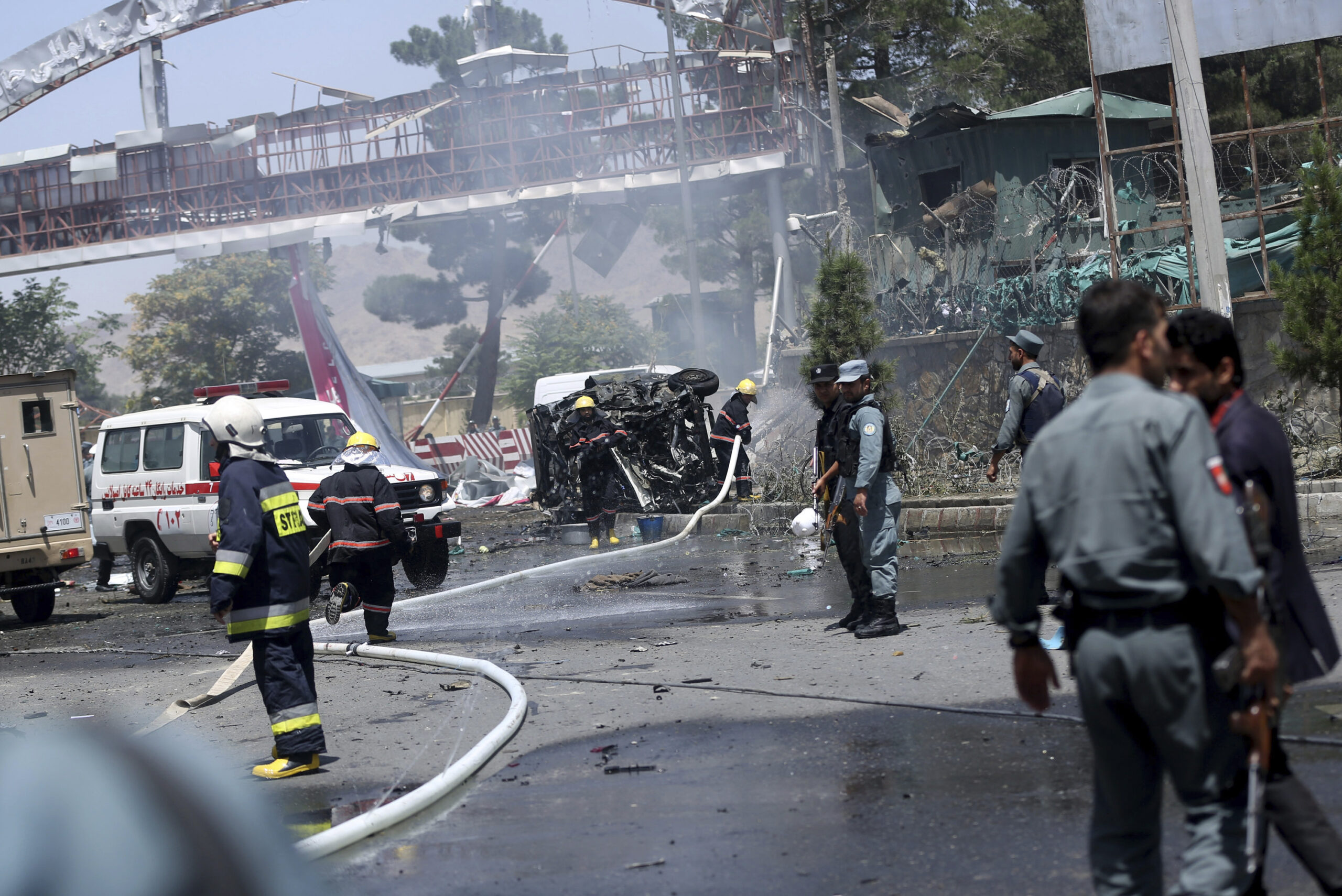 FILE - Afghan fire fighters extinguish vehicles on fire after an attack at the main gate of Interna...